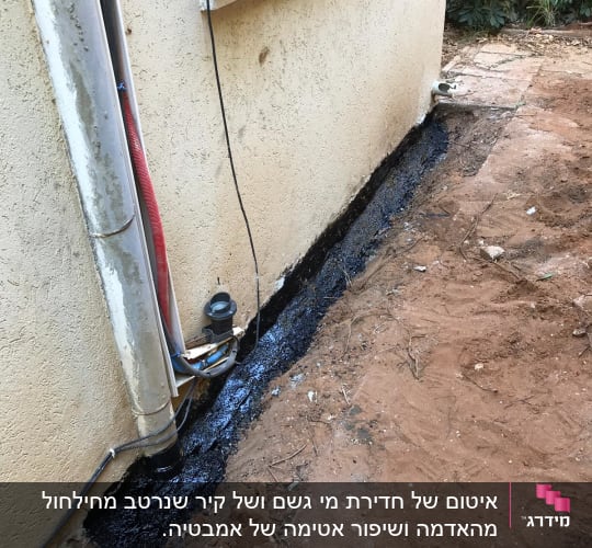 איטום קיר חיצוני עם חומר שחור ליד צינור